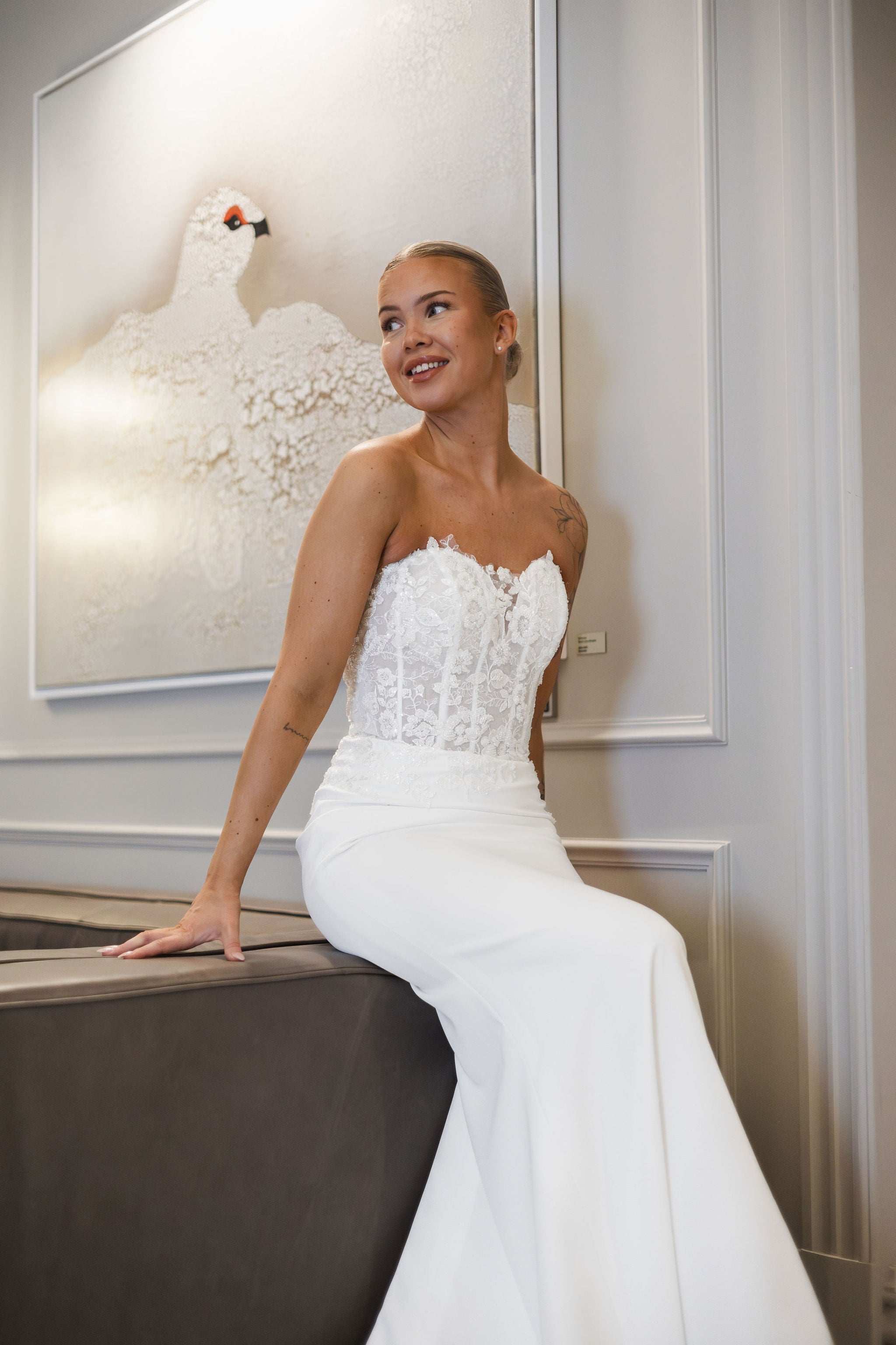 Olkaimeton tyköistuva häämekko pitsiyläosalla ja laahuksella.