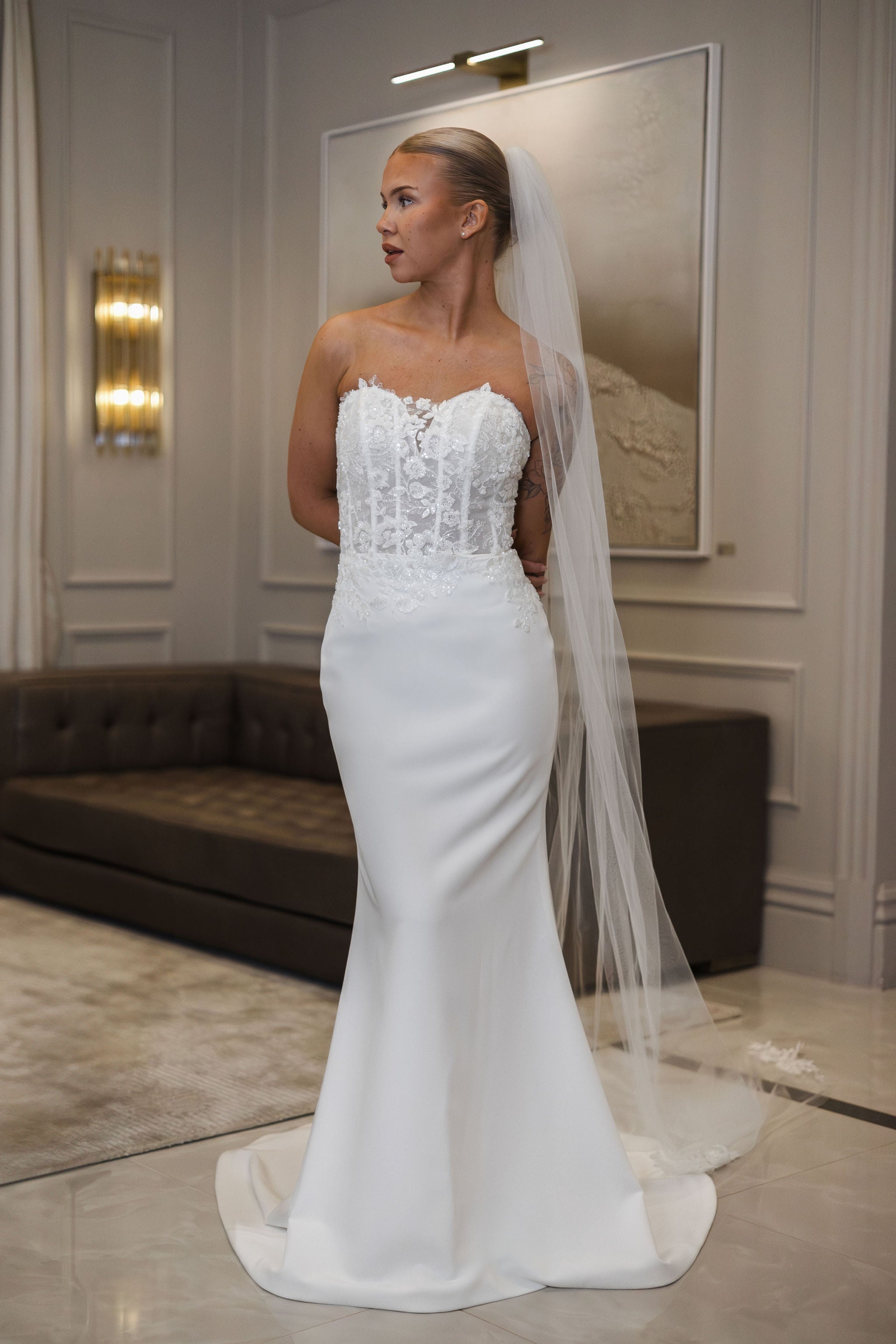 Olkaimeton tyköistuva häämekko pitsiyläosalla ja laahuksella.