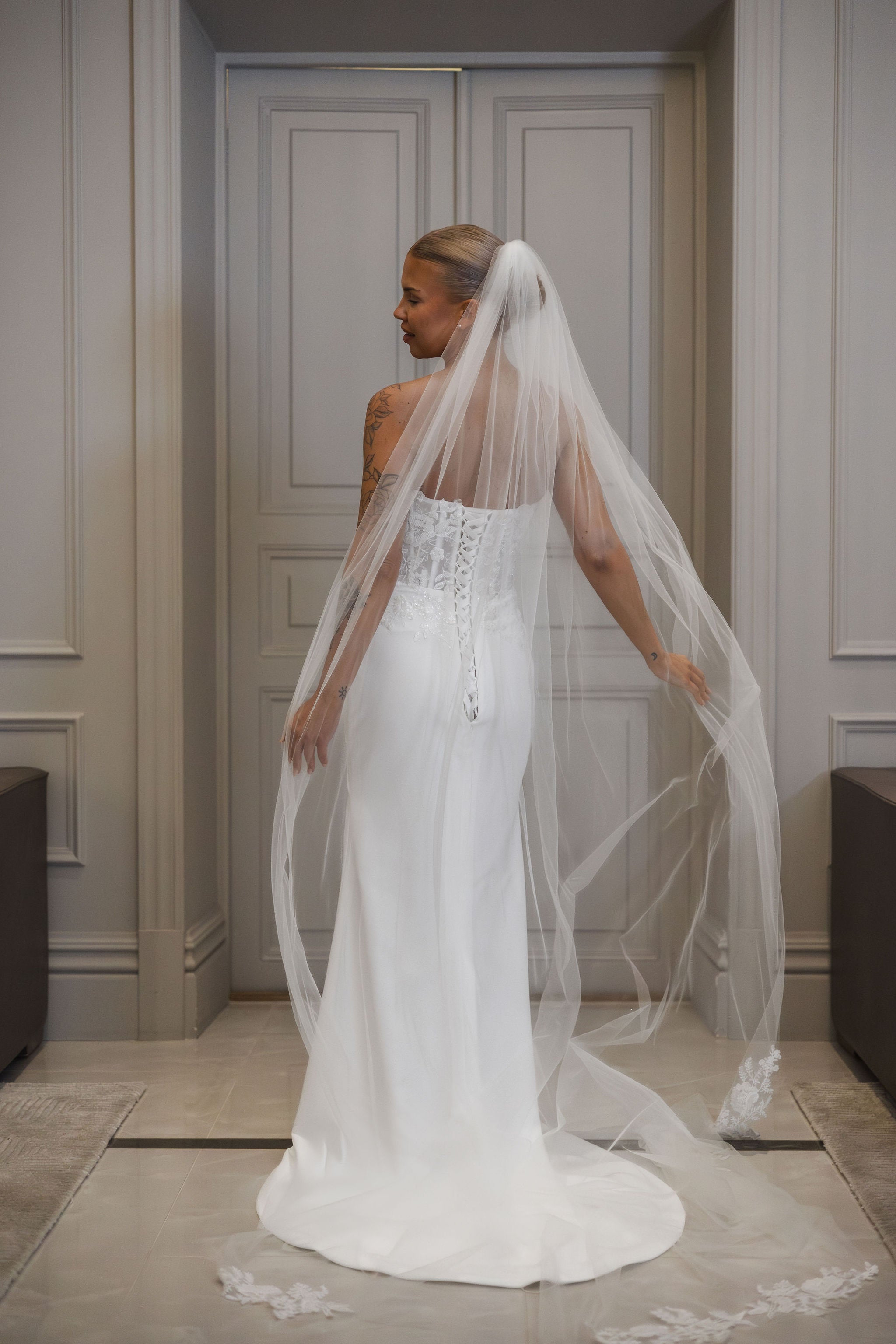 Olkaimeton tyköistuva häämekko pitsiyläosalla ja laahuksella, takaa.