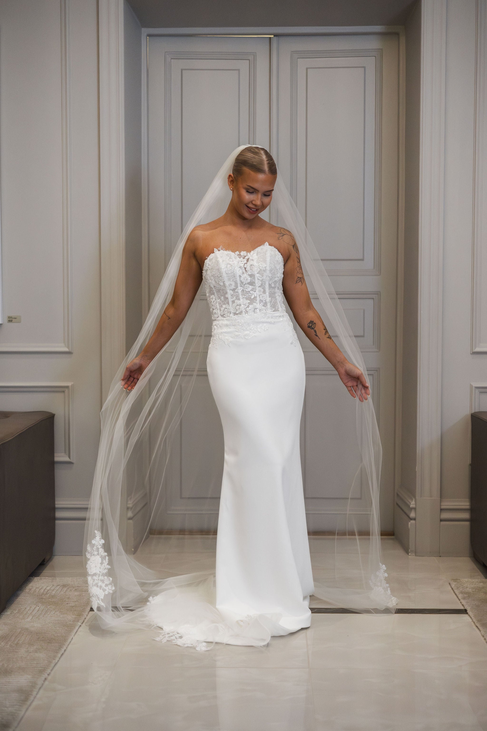 Olkaimeton tyköistuva häämekko pitsiyläosalla ja laahuksella.