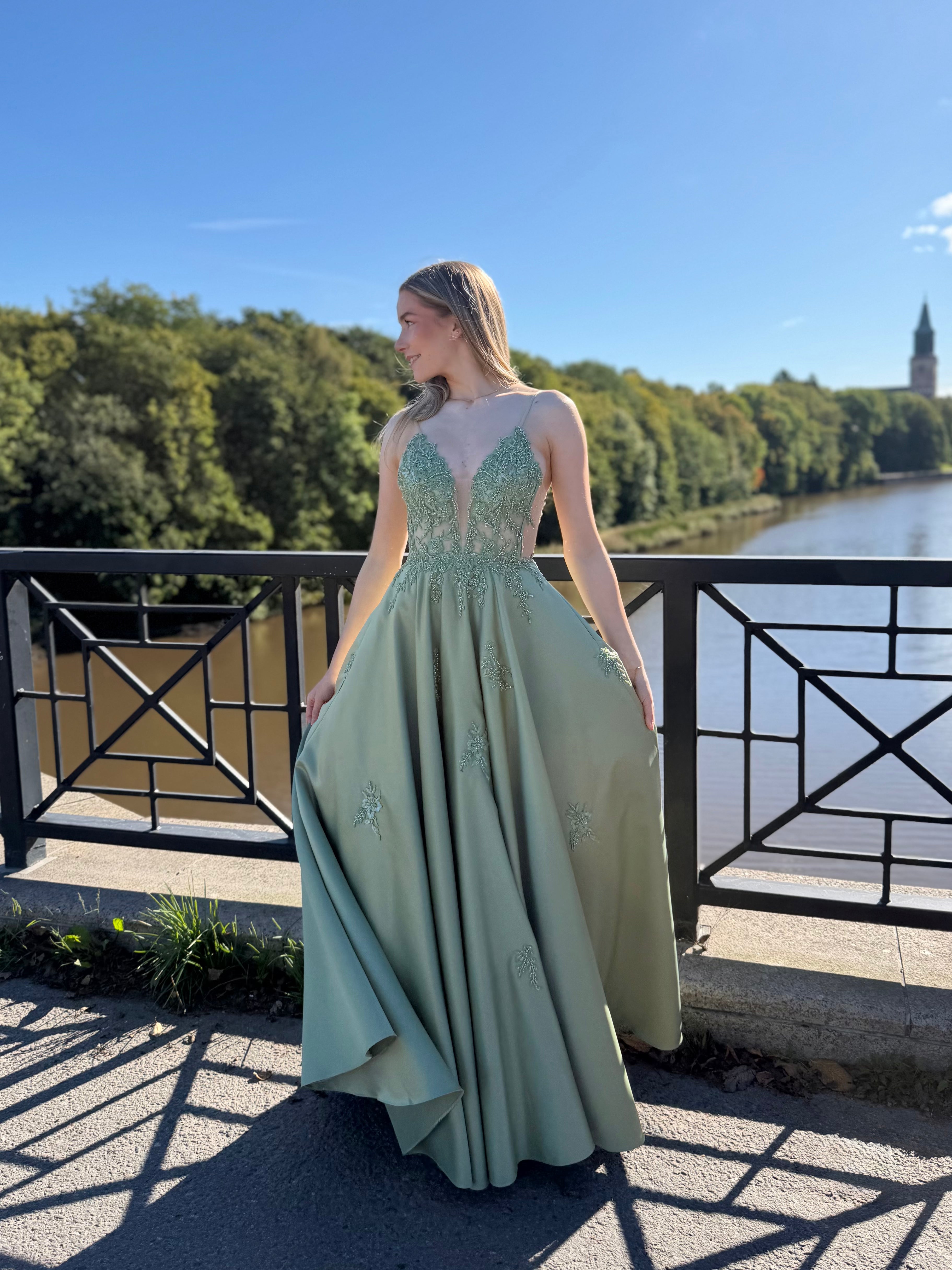 Oliivinvihreä vanhojentanssimekko pitsiyläosalla ja suoralla satiinihelmalla.