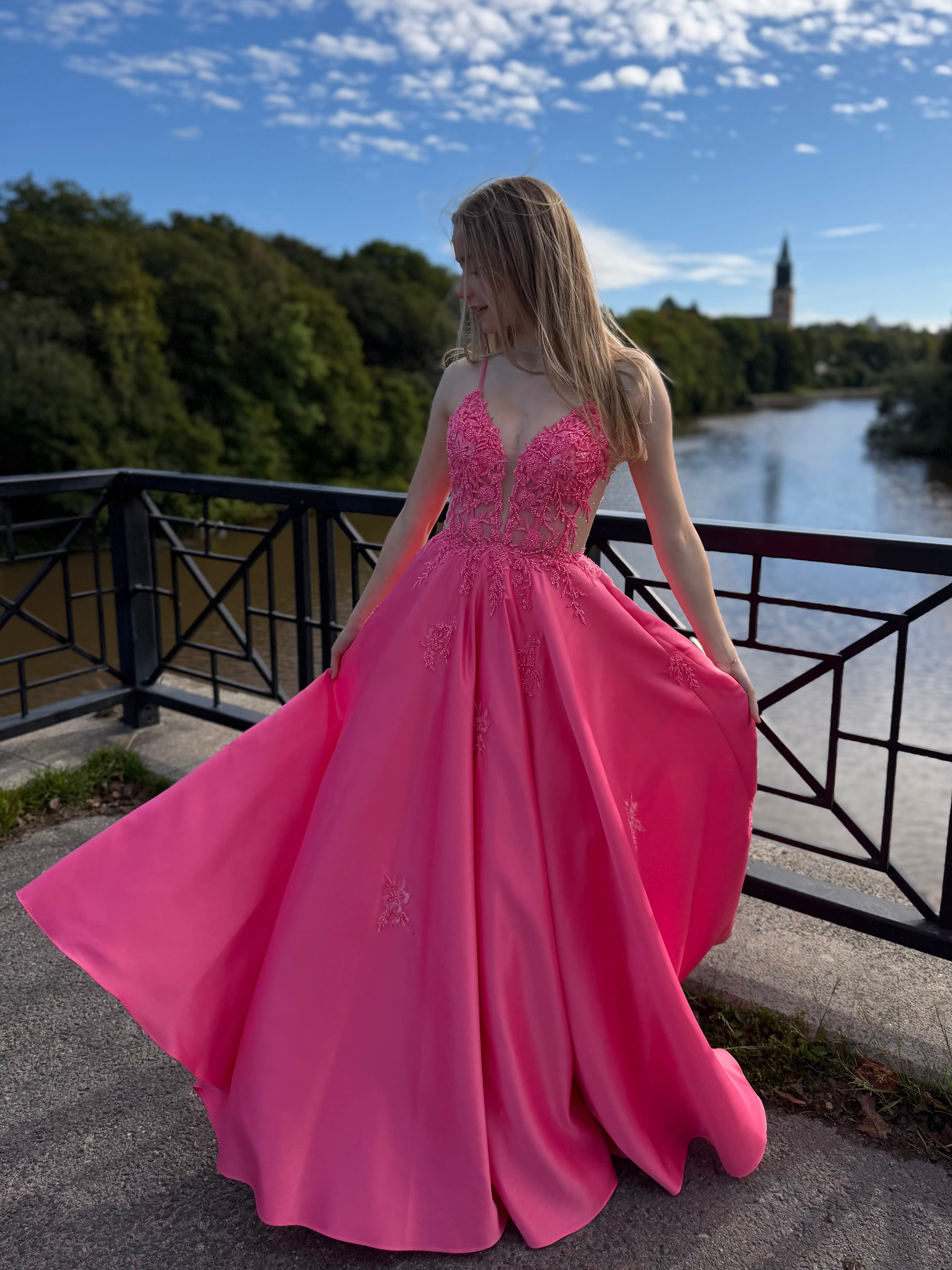 Fuksianpinkki vanhojentanssimekko pitsiyläosalla ja suoralla satiinihelmalla.