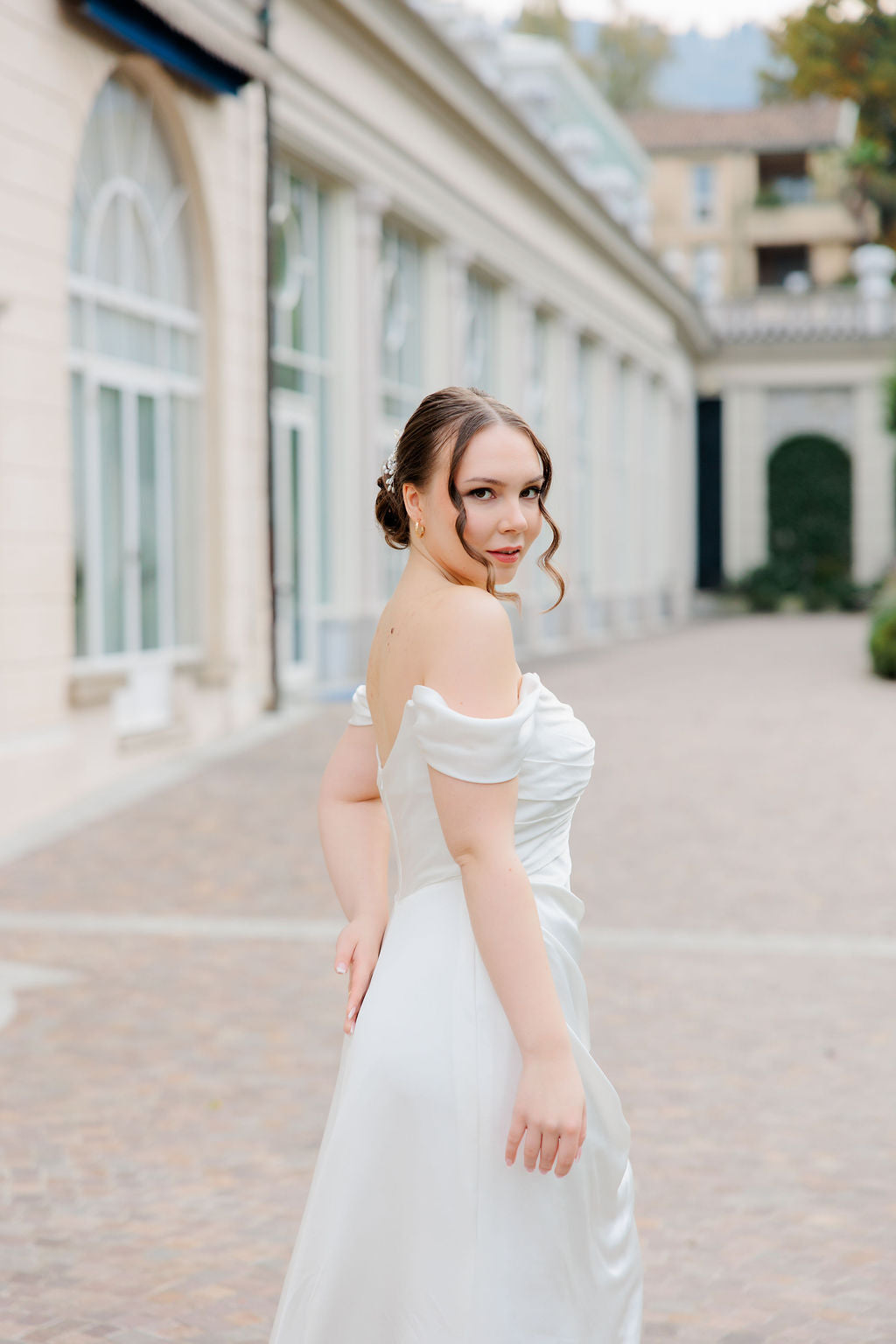 Laskeutuva off shoulder -häämekko tyköistuvalla yläosalla, sivusta.