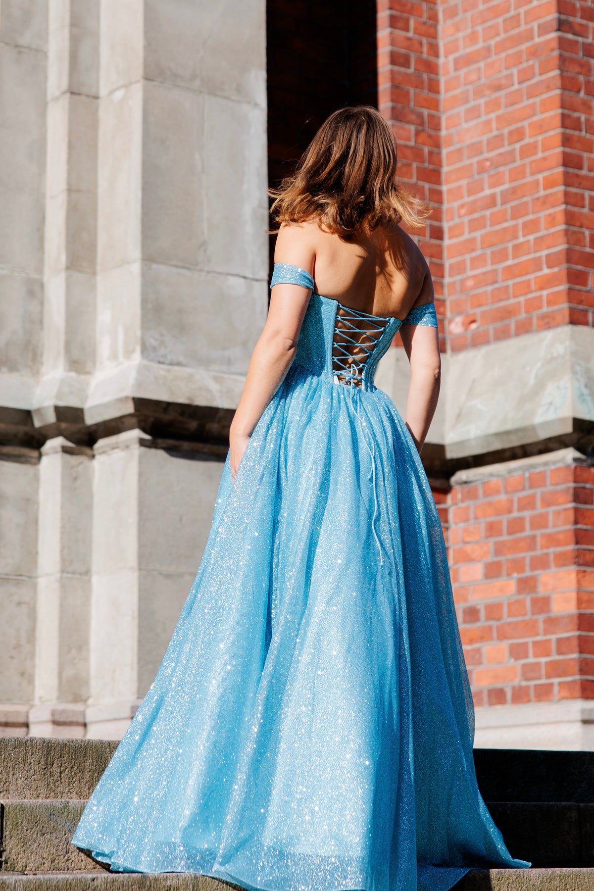 Sininen off shoulder -mallinen vanhojentanssimekko glitterkankaasta ja suoralla helmalla.